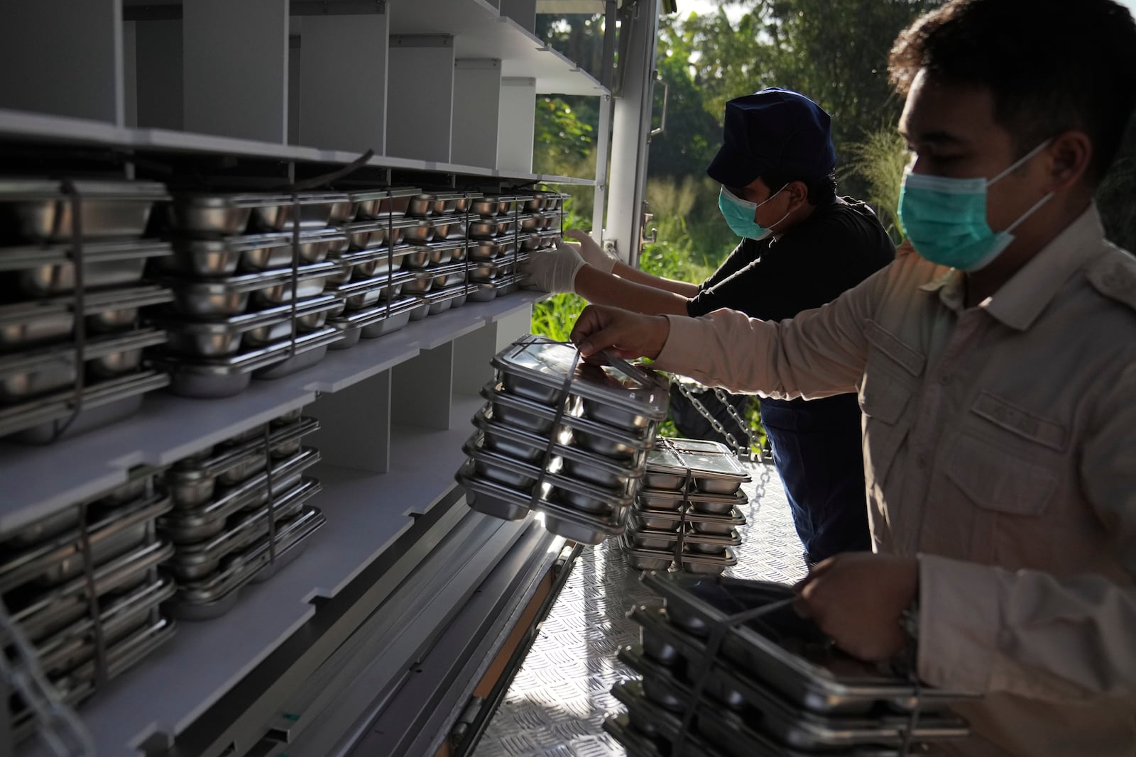 Workers load food containers to be distributed to schools during the kick off of President Prabowo Subianto's ambitious free meal program to feed children and pregnant women nationwide despite critics saying that its required logistics could hurt Indonesia's state finances and economy, at an elementary school in Depok, West Java, Indonesia, Monday, Jan. 6, 2025. (AP Photo/Dita Alangkara)