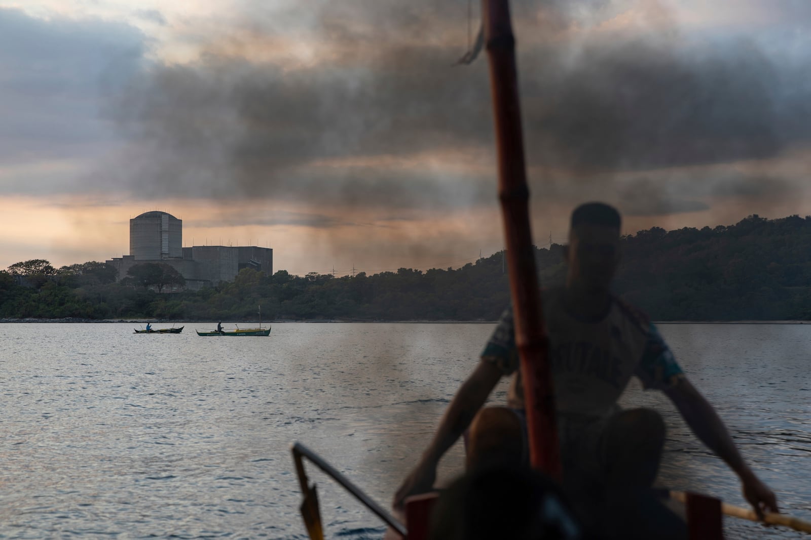 Smoke rises as a fisherman fires up the diesel motor of his boat in front of the Bataan Nuclear Power Plant in the Philippines on Sunday, Jan. 19, 2025. (AP Photo/Anton L. Delgado)