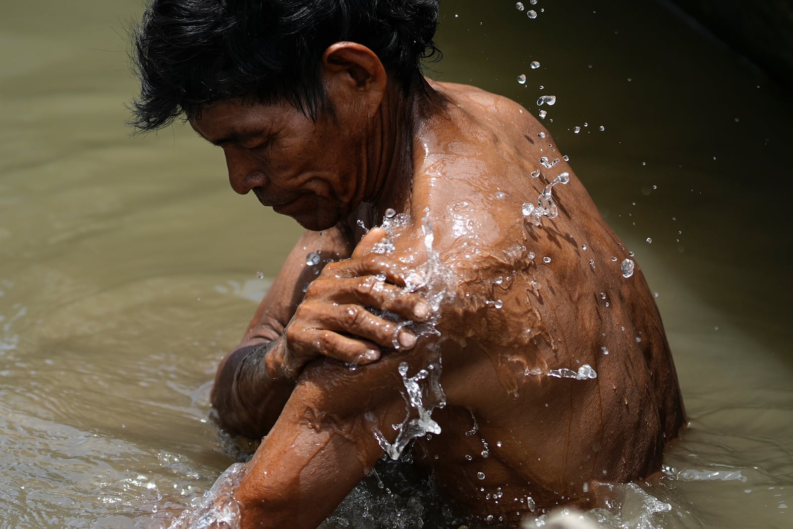 An Indigenous man from the Tikuna community bathes in the Amazon River, in Loma Linda, Colombia, Sunday, Oct. 20, 2024. (AP Photo/Ivan Valencia)