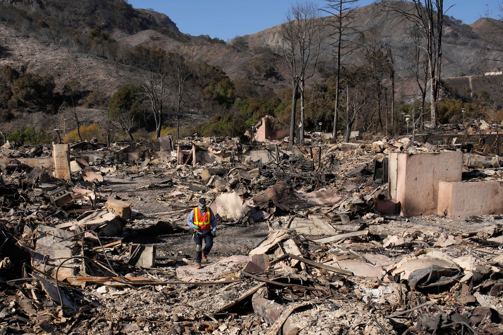 A worker surveys the damage from the Palisades Fire in the Pacific Palisades neighborhood of Los Angeles, Monday, Jan. 13, 2025. (AP Photo/John Locher)