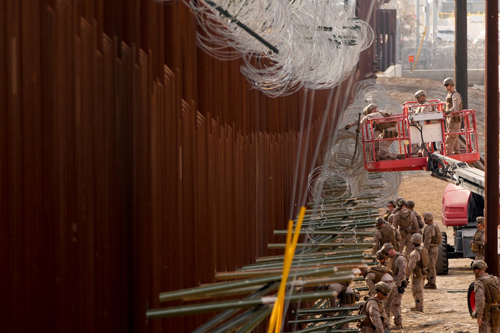 U.S. Marines install barbed wire along the border fence Friday, Jan. 31, 2025, in San Diego. (AP Photo/Jae C. Hong)