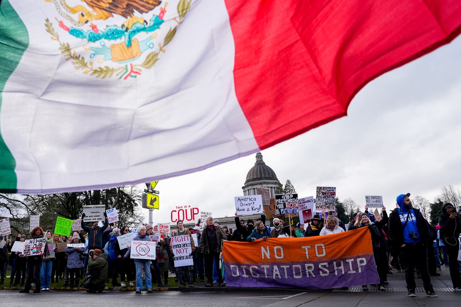 A person holds the flag of Mexico as people gather to protest against the Trump administration and Project 2025 near the Washington State Capitol building Wednesday, Feb. 5, 2025, in Olympia, Wash. (AP Photo/Lindsey Wasson)