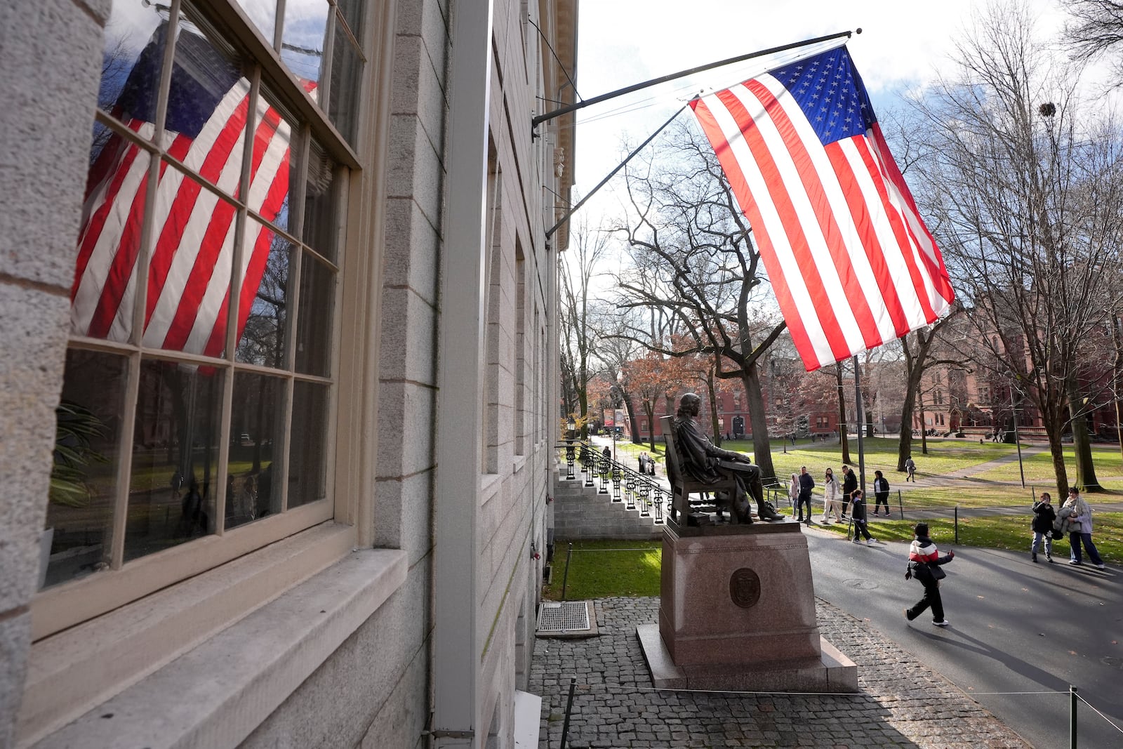 People walk past the John Harvard statue in Harvard Yard, Tuesday, Dec. 17, 2024, on the campus of Harvard University in Cambridge, Mass. (AP Photo/Steven Senne)