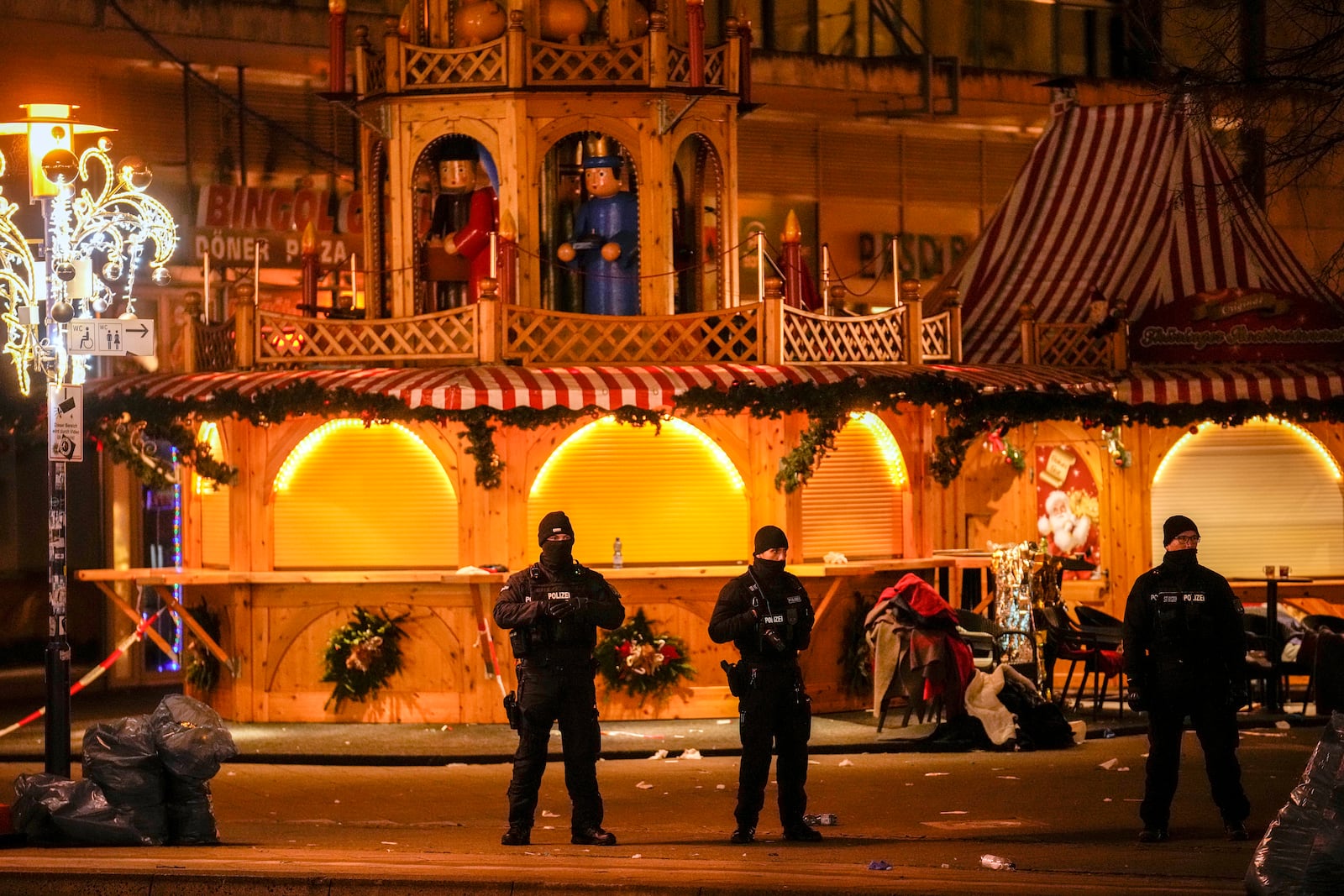 Security guards stand in front of a cordoned-off Christmas Market after a car crashed into a crowd of people, in Magdeburg, Germany, Saturday early morning, Dec. 21, 2024. (AP Photo/Ebrahim Noroozi)