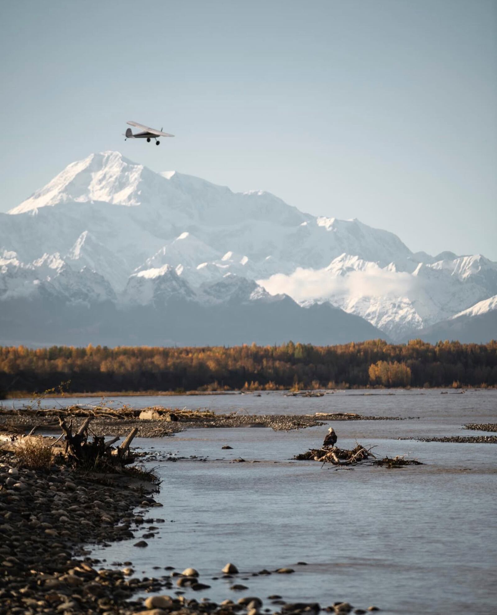 In this photo provided by Andrew Esola, Joe McAneney flies his airplane over the Chulitna River toward Mount McKinley near Talkeetna, Alaska, Sept. 22, 2022. (Andrew Esola via AP)