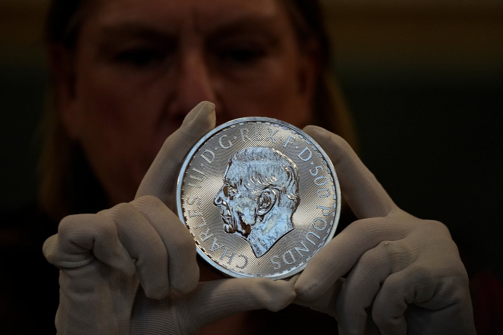 A warden inspects a 500 Pounds commemorative coin during the "Trial of the Pyx,'' a ceremony that dates to the 12th Century in which coins are weighed in order to make certain they are up to standard, at the Goldsmiths' Hall in London, Tuesday, Feb. 11, 2025.(AP Photo/Frank Augstein)