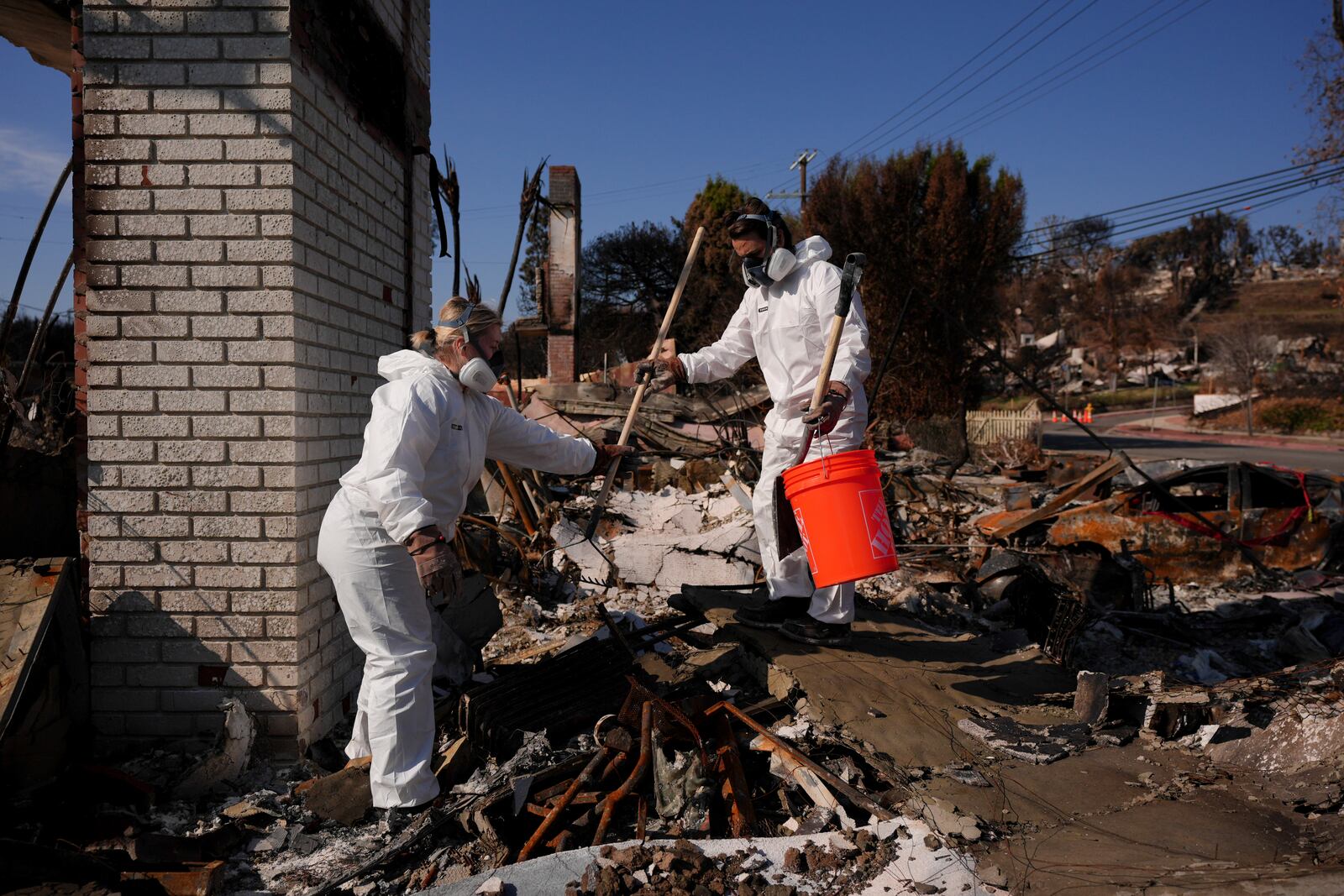 Katelyn White, left, and her husband John Borbone search through their fire-ravaged property after the Palisades Fire in the Pacific Palisades neighborhood of Los Angeles, Tuesday, Jan. 28, 2025. (AP Photo/Jae C. Hong)