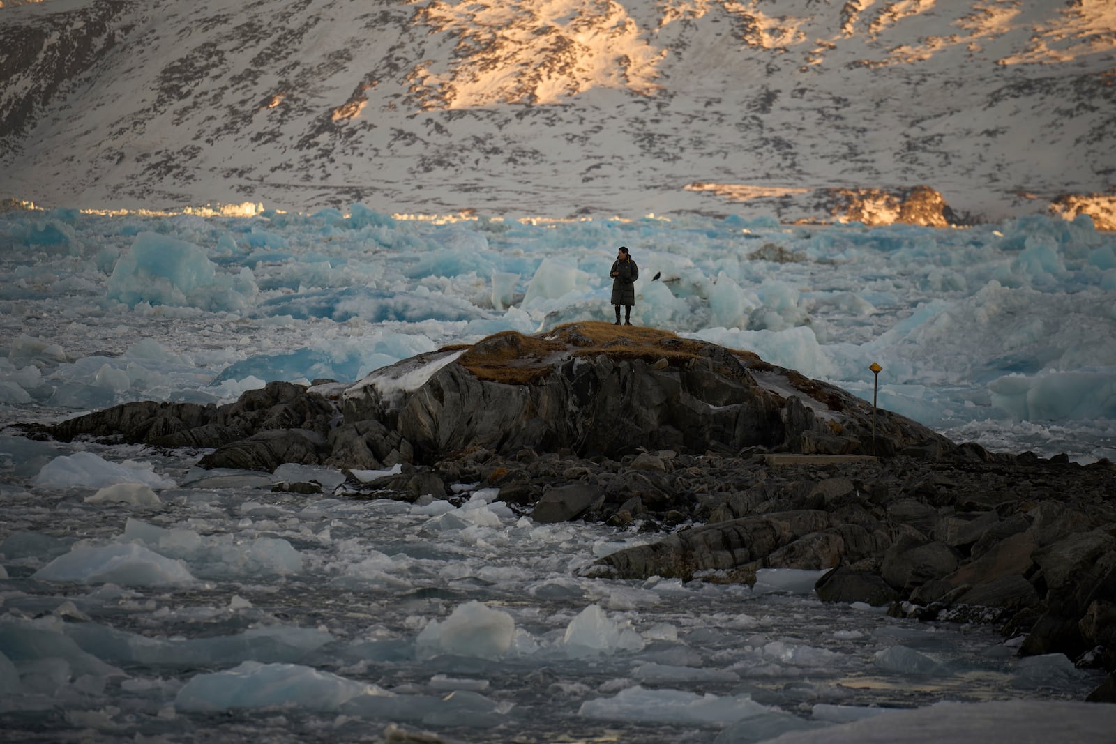 A resident watches as pieces of ice pile up blocking the access of the port of Nuuk, Greenland, Tuesday, Feb. 18, 2025. (AP Photo/Emilio Morenatti)