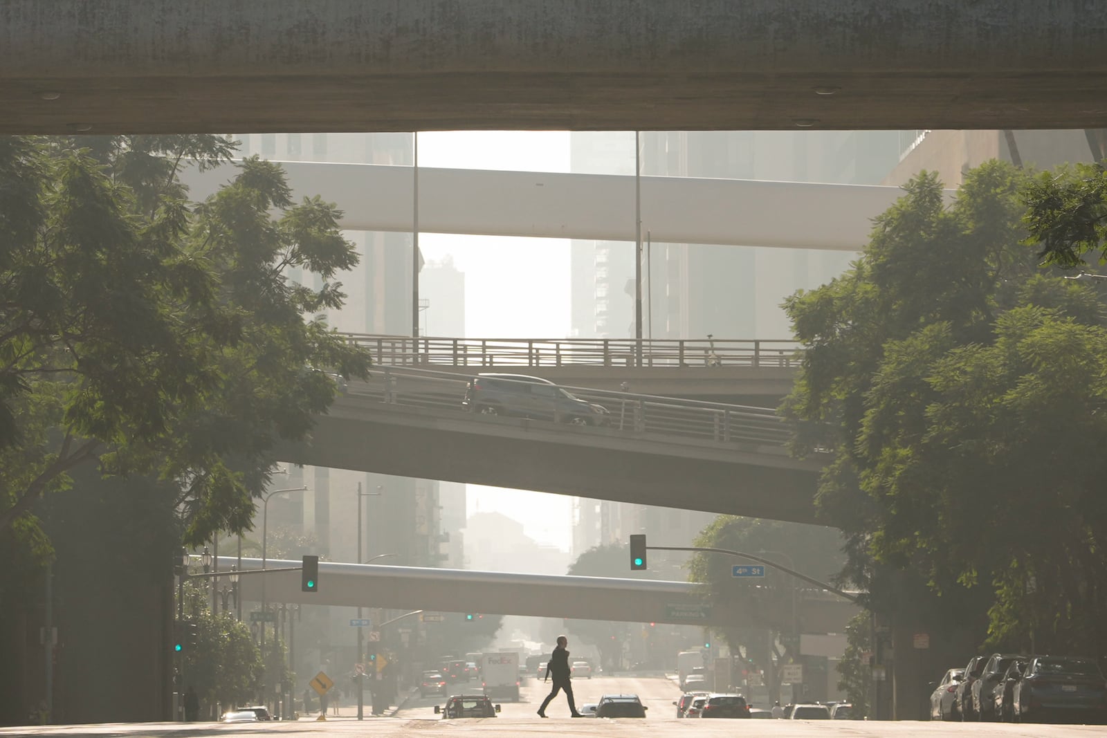 A person crosses a street as smog fills the air Wednesday, Dec. 4, 2024, in Los Angeles. (AP Photo/Andy Bao)