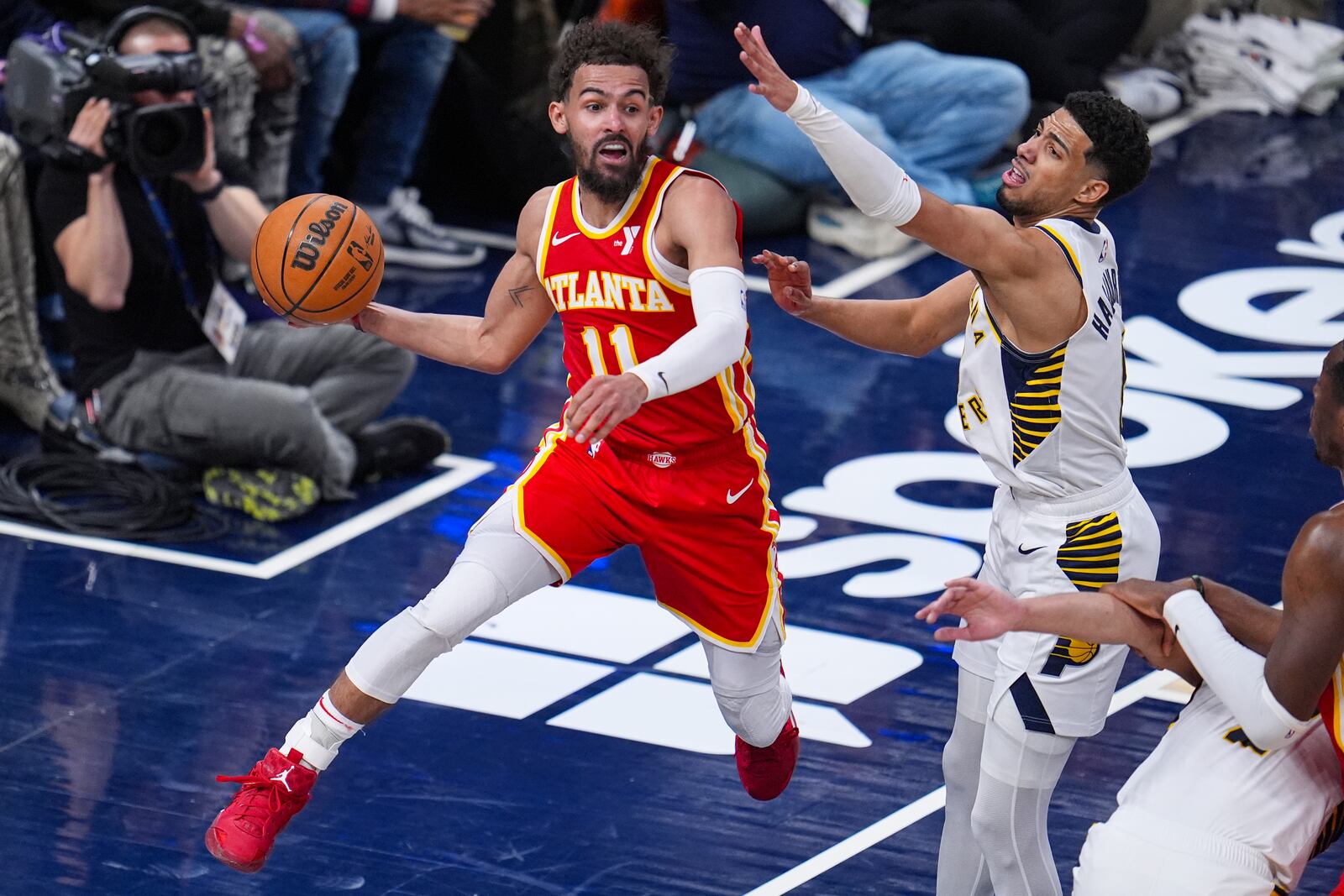 Atlanta Hawks guard Trae Young (11) goes around Indiana Pacers guard Tyrese Haliburton (0) to make a pass during the second half of an NBA basketball game in Indianapolis, Saturday, Feb. 1, 2025. (AP Photo/Michael Conroy)