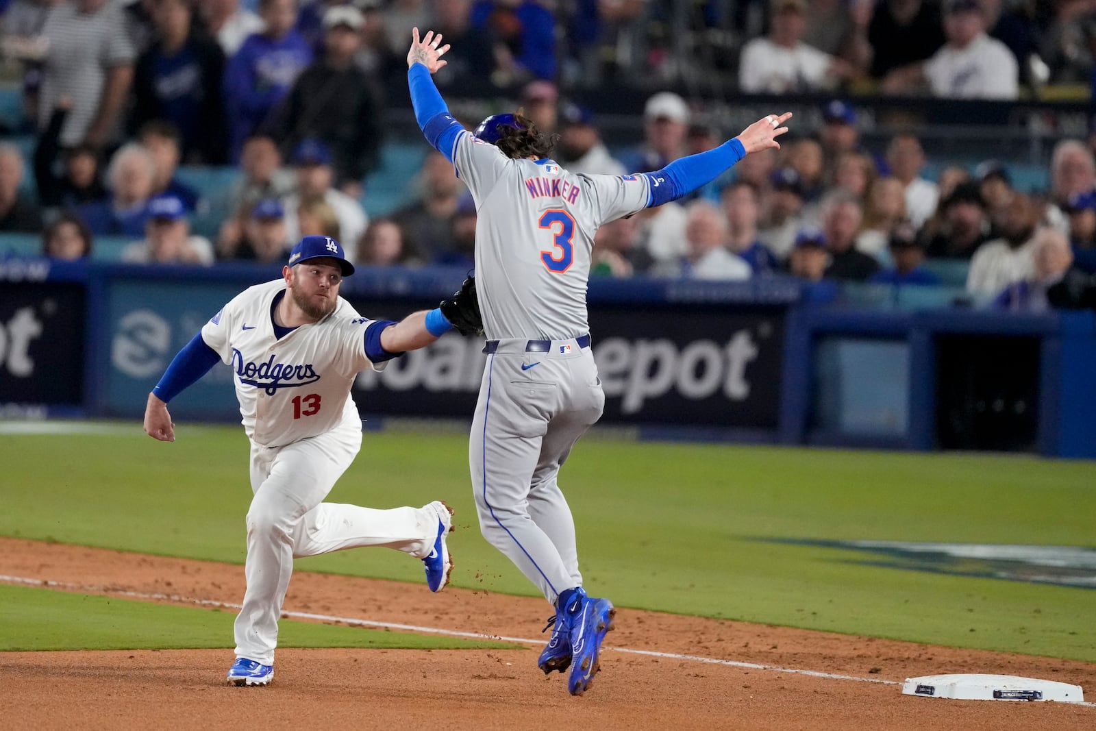 Los Angeles Dodgers third baseman Max Muncy tags out New York Mets' Jesse Winker at third base after a single by Jose Iglesias during the fifth inning in Game 1 of a baseball NL Championship Series, Sunday, Oct. 13, 2024, in Los Angeles. (AP Photo/Mark J. Terrill)