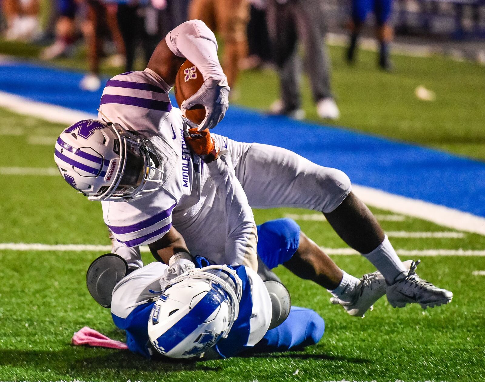 Middletown’s Josh Bryant goes over Hamilton’s James Turner for a touchdown Friday night at Virgil Schwarm Stadium in Hamilton. The visiting Middies took a 15-14 defeat. NICK GRAHAM/STAFF