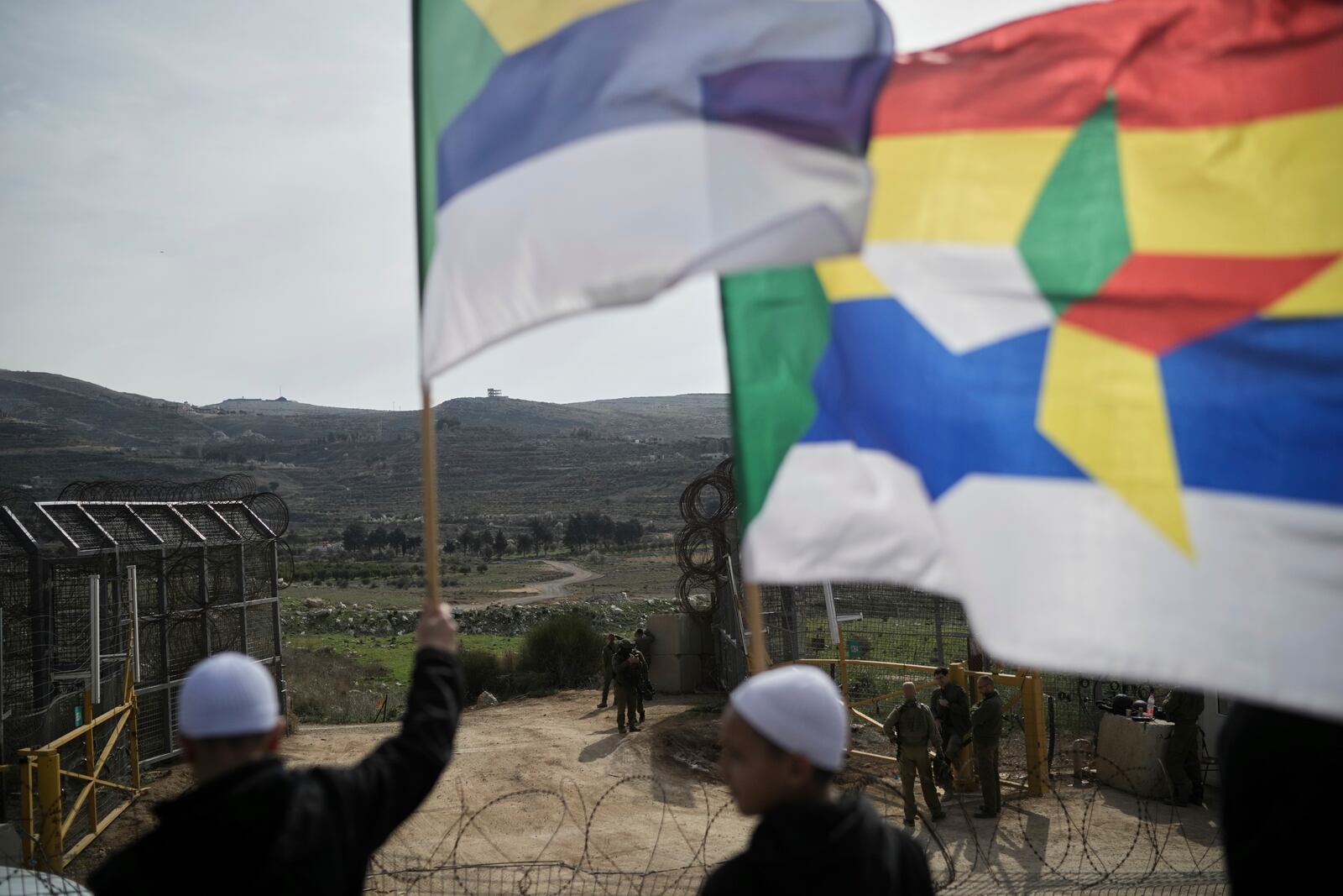 Members of the Druze community and clerics wait near the border for buses carrying members of the Syrian Druze community to cross from Syria in the village of Majdal Shams, in the Israeli-controlled Golan Heights, Friday, March 14, 2025. (AP Photo/Leo Correa)