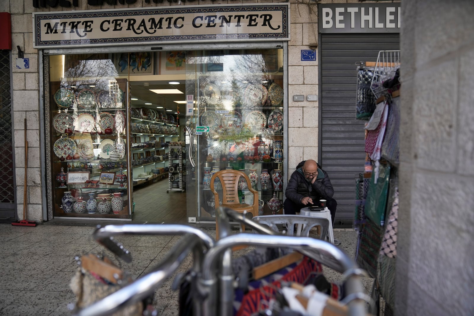 A man waits outside a souvenir shop near the Church of the Nativity, where Christians believe Jesus Christ was born, ahead of Christmas in the West Bank city of Bethlehem, Saturday Dec. 21, 2024. (AP Photo/Mahmoud Illean)