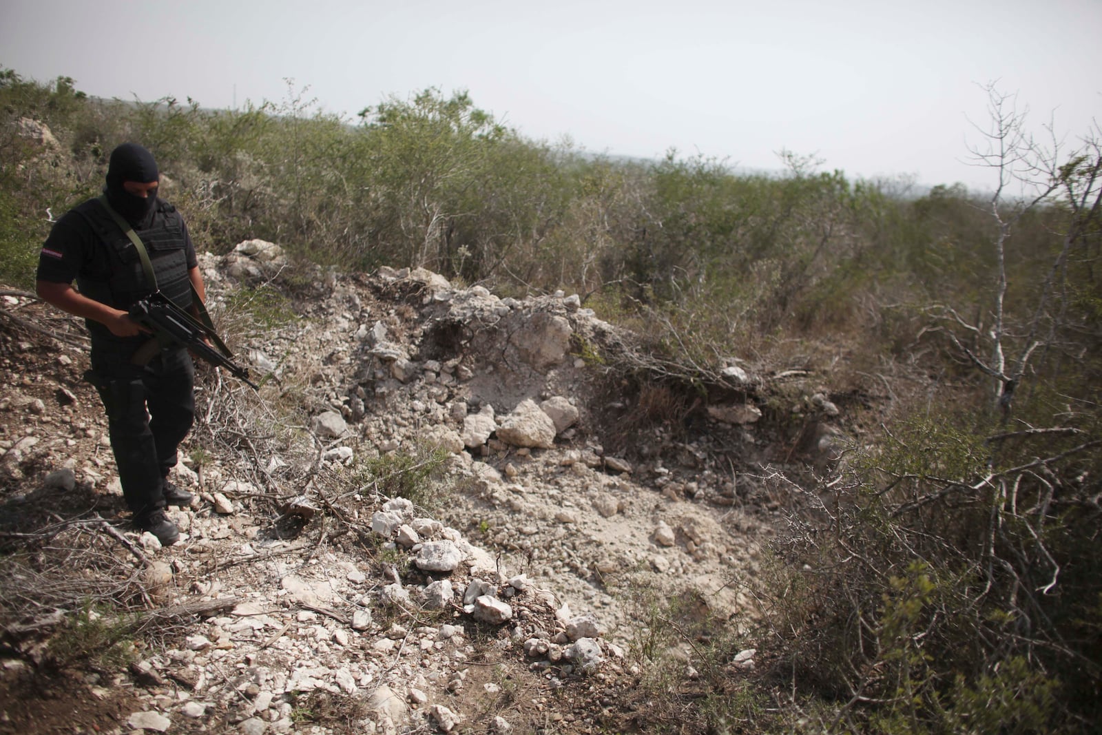 FILE - An officer walks past a hole that police say was used as a mass grave, near San Fernando, Tamaulipas state, Mexico, April 27, 2011. (AP Photo/Alexandre Meneghini, File)