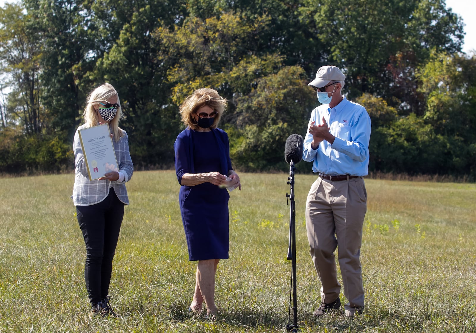 Burt Logan presents an award of merit from the State Historic Preservation Office of the Ohio History Connection Wednesday, October 7, 2020, to Barbara Wilks, left, and Nanci Lanni, middle, with The Harry T. Wilks Family Foundation for acquisition of the Fortified Hill Earthworks in Butler County. The Fortified Hill Earthworks was donated to nearby Pyramid Hill Sculpture Park to ensure its preservation. NICK GRAHAM / STAFF