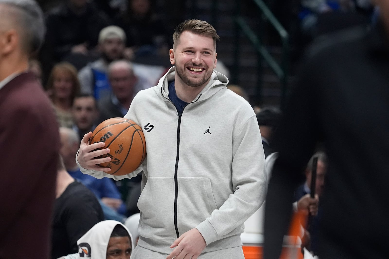 Injured Dallas Mavericks guard Luka Doncic smiles as he holds the game ball in a time out during the first half of an NBA basketball game against the Minnesota Timberwolves Wednesday, Jan. 22, 2025, in Dallas. (AP Photo/LM Otero)