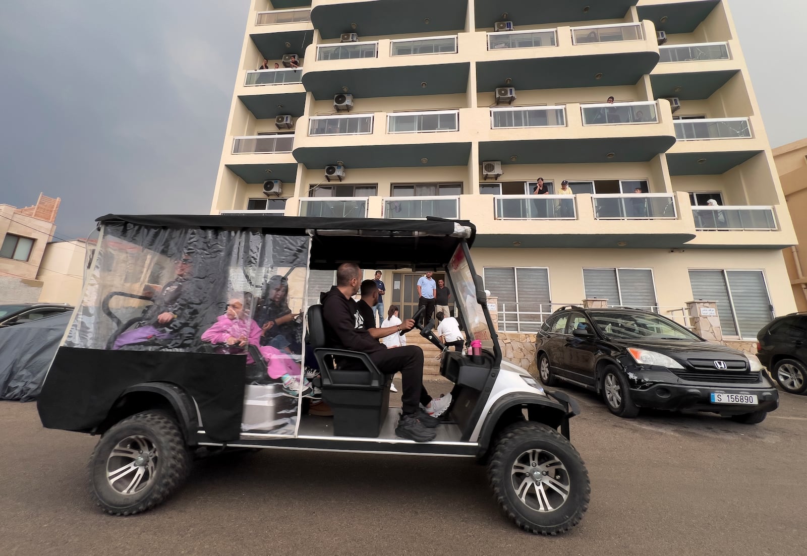 Residents ride a golf cart, as they pass in front of a building in Batroun, northern Lebanon, Saturday, Nov. 2, 2024, where Lebanese officials say a ship captain was taken away by a group of armed men who landed on a coast north of Beirut and they're investigating whether Israel was involved. (AP Photo/Hussein Malla)