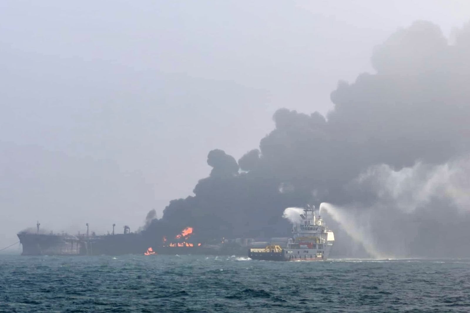 This image provided by Bartek Śmiałek shows a ship trying to extinguish the fire as smoke billows from a vessel after a cargo ship hit a tanker carrying jet fuel off eastern England on Monday, March 10, 2025 setting both ablaze and sending fuel pouring into the North Sea. (Bartek Śmiałek via AP)