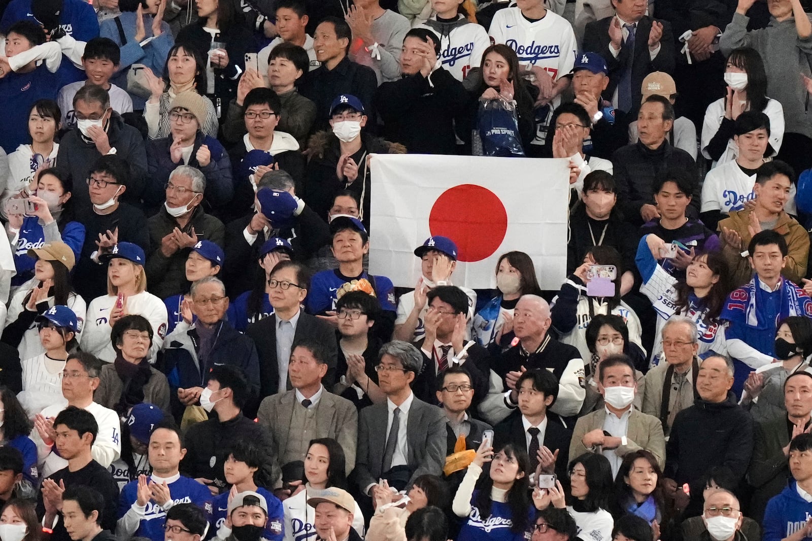 Fans hold up a Japanese national flag during team intorductions before an MLB Tokyo Series baseball game between the Los Angeles Dodgers and Chicago Cubs in Tokyo, Japan, Wednesday, March 19, 2025. (AP Photo/Eugene Hoshiko)