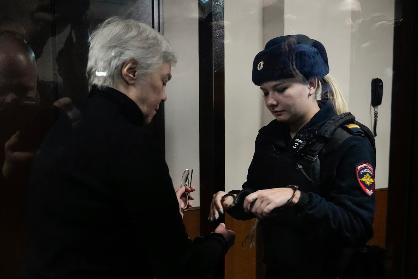 A police officer removes handcuffs form hands of Pediatrician Nadezhda Buyanova, accused of spreading false information about the army, prior to a hearing in the Tushinsky District Court in Moscow, Russia, Tuesday, Nov. 12, 2024. (AP Photo/Pavel Bednyakov)