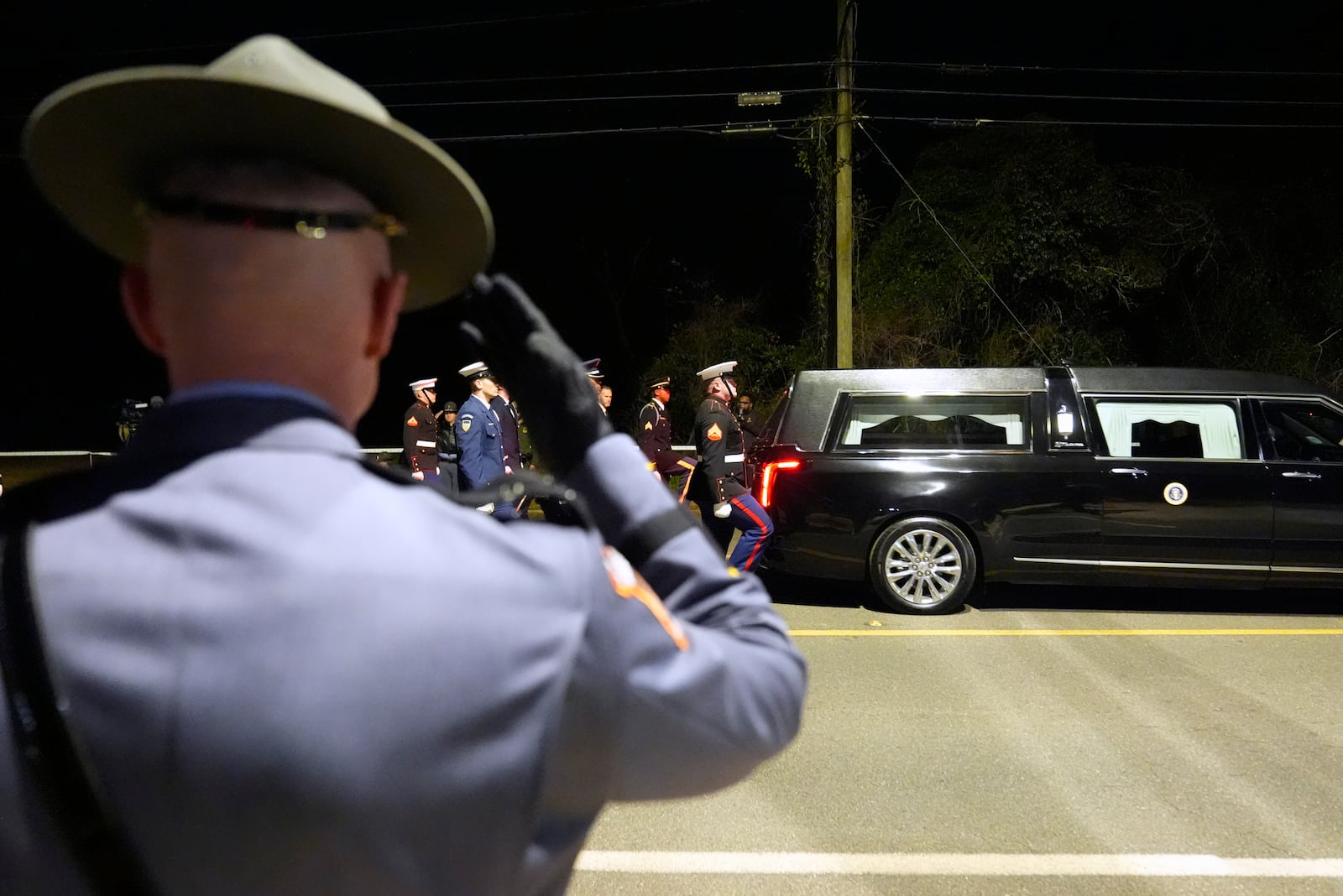 A member of the Georgia State Patrol salutes as the hearse carrying former President Jimmy Carter approaches the Carter residence, where he will be buried, in Plains, Ga., Thursday, Jan. 9, 2025. (AP Photo/Alex Brandon, Pool)