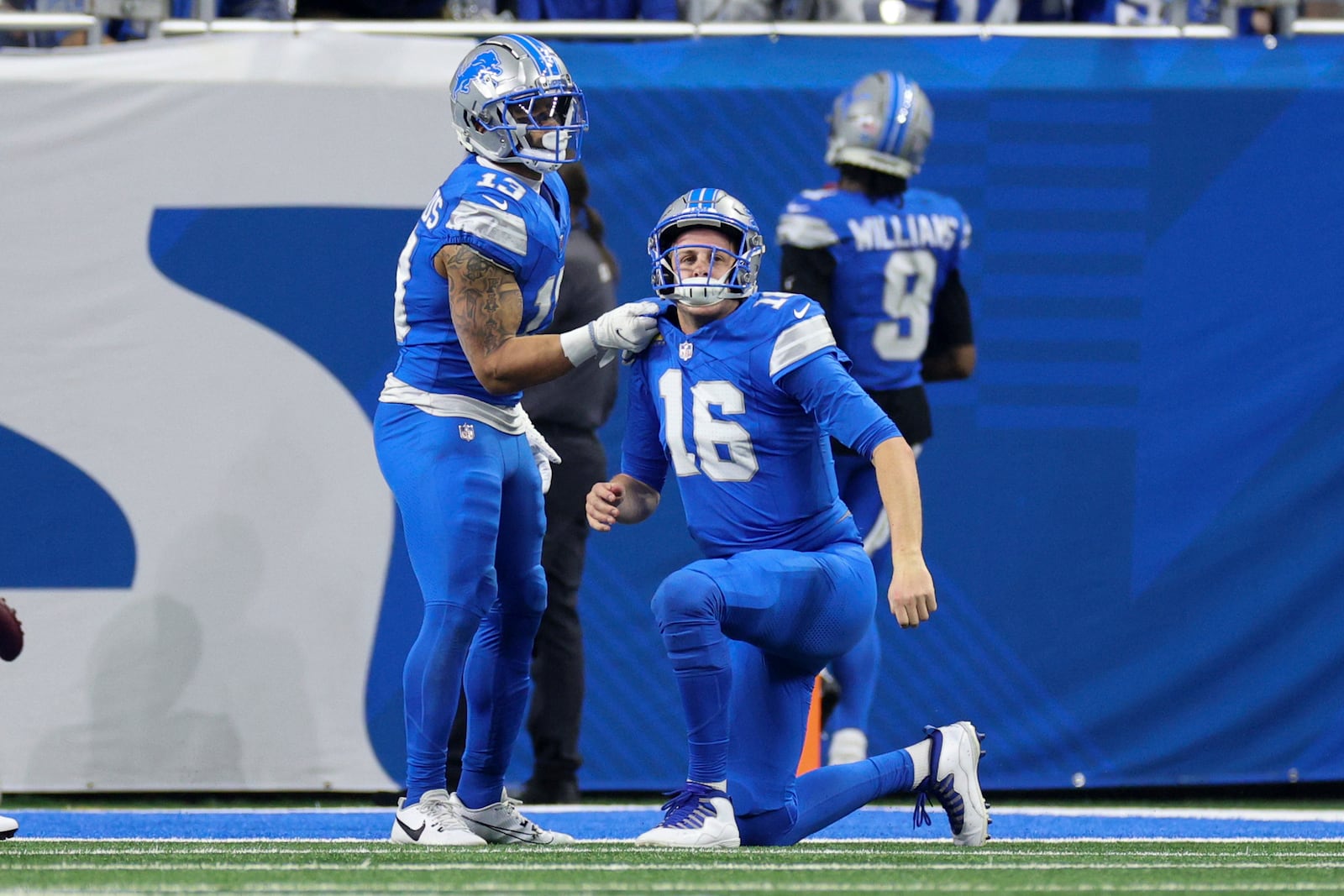 Detroit Lions running back Craig Reynolds (13) helps quarterback Jared Goff (16) up against the Washington Commanders during the first half of an NFL football divisional playoff game, Saturday, Jan. 18, 2025, in Detroit. (AP Photo/Mike Mulholland)