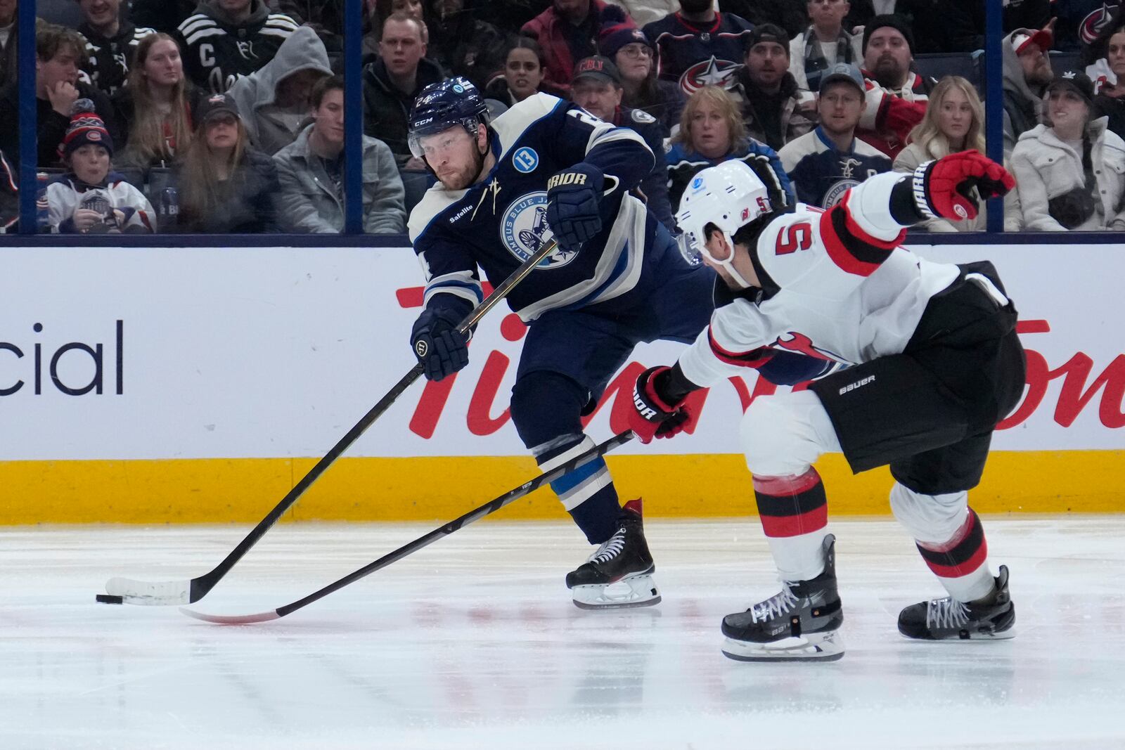 Columbus Blue Jackets right wing Mathieu Olivier, left, shoots as New Jersey Devils defenseman Brenden Dillon (5) defends in the second period of an NHL hockey game Thursday, Dec. 19, 2024, in Columbus, Ohio. (AP Photo/Sue Ogrocki)