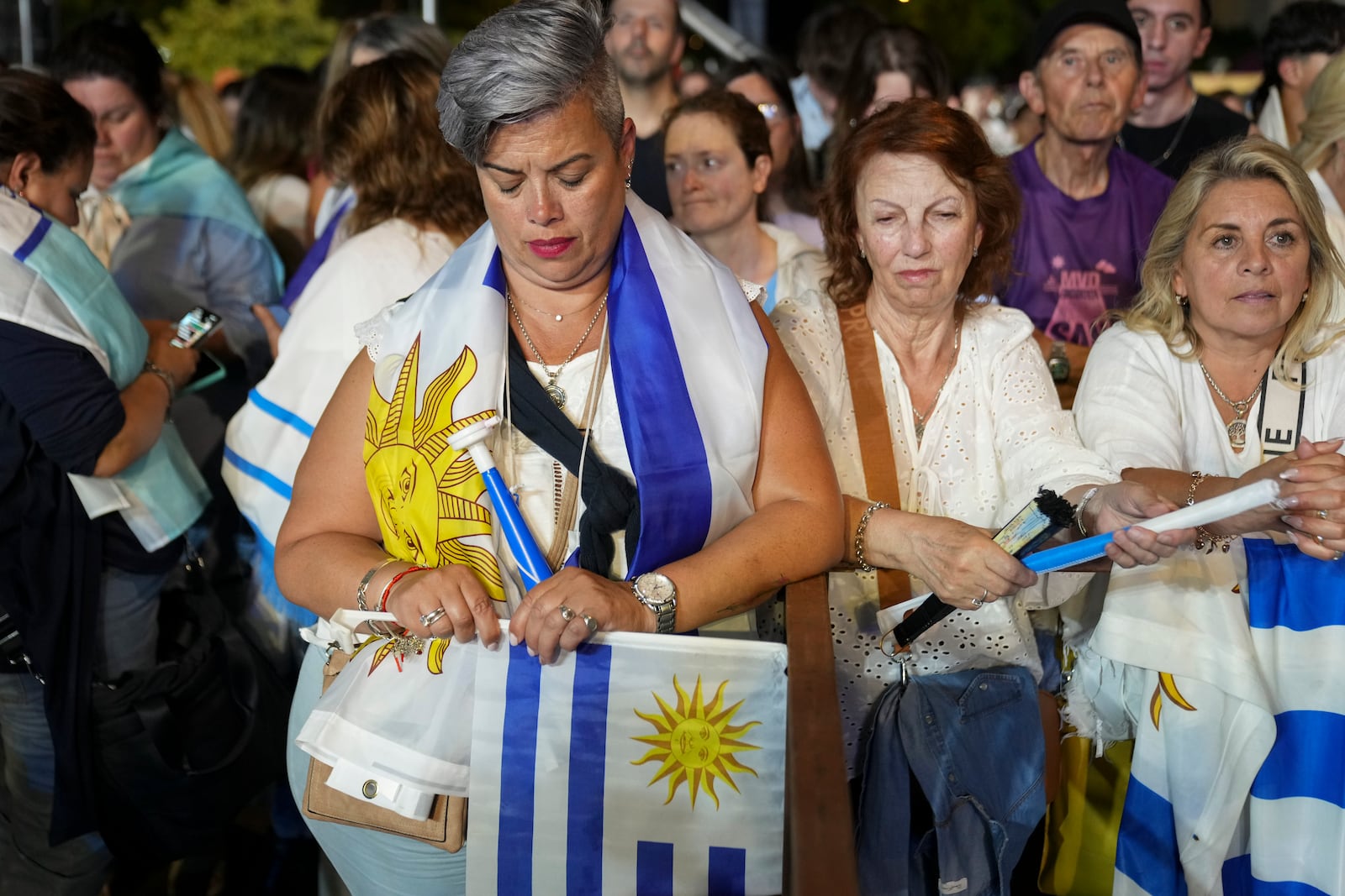 Supporters of Alvaro Delgado, presidential candidate for the ruling National Party, listen to early results from pollsters at the party's campaign night headquarters in Montevideo, Uruguay, after polls closed in the presidential run-off election, Sunday, Nov. 24, 2024. (AP Photo/Matilde Campodonico)