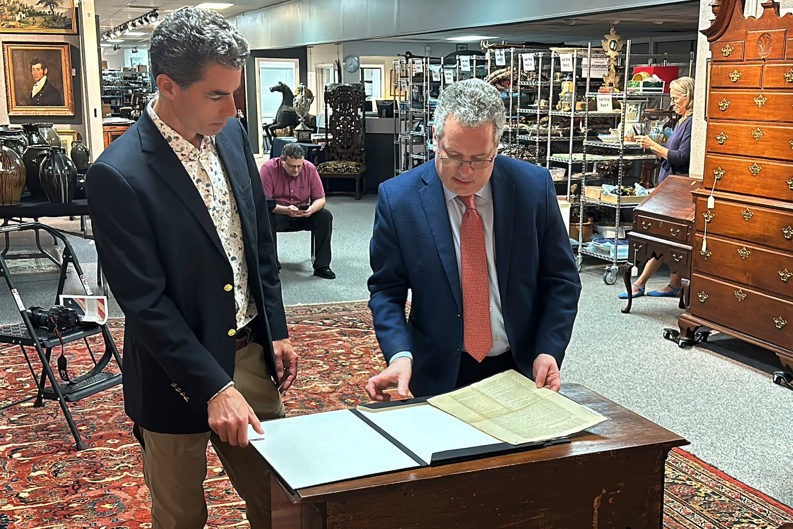 FILE - Auctioneer Andrew Brunk, left, and historian Seth Kaller, right show off a 1787 copy of the U.S. Constitution that will be put up for auction at Brunk Auctions in Asheville, N.C., on Sept. 5, 2024. (AP Photo/Jeffrey Collins, file)