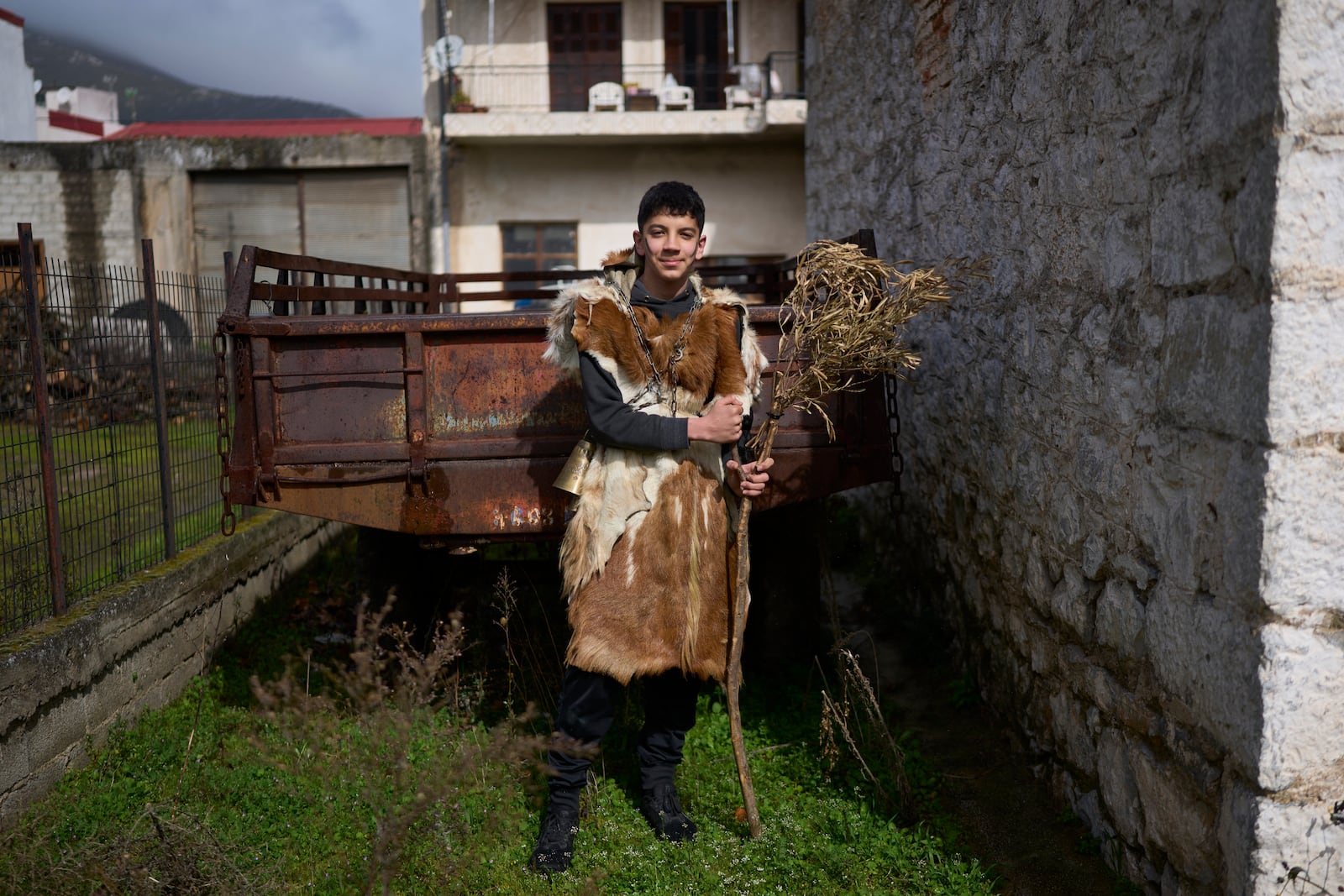 Loukas Bellos, 15, poses for a portrait, dressed in animal skins and heavy bronze bells, as part of carnival celebrations in Distomo, a village in central Greece, on Monday, March 3, 2025. (AP Photo/Petros Giannakouris)