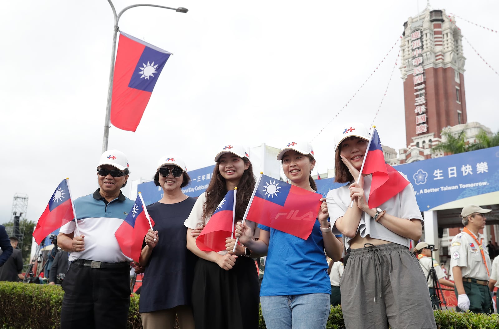 People pose with Taiwan's national flags for a photo during National Day celebrations in front of the Presidential Building in Taipei, Taiwan, Thursday, Oct. 10, 2024. (AP Photo/Chiang Ying-ying)