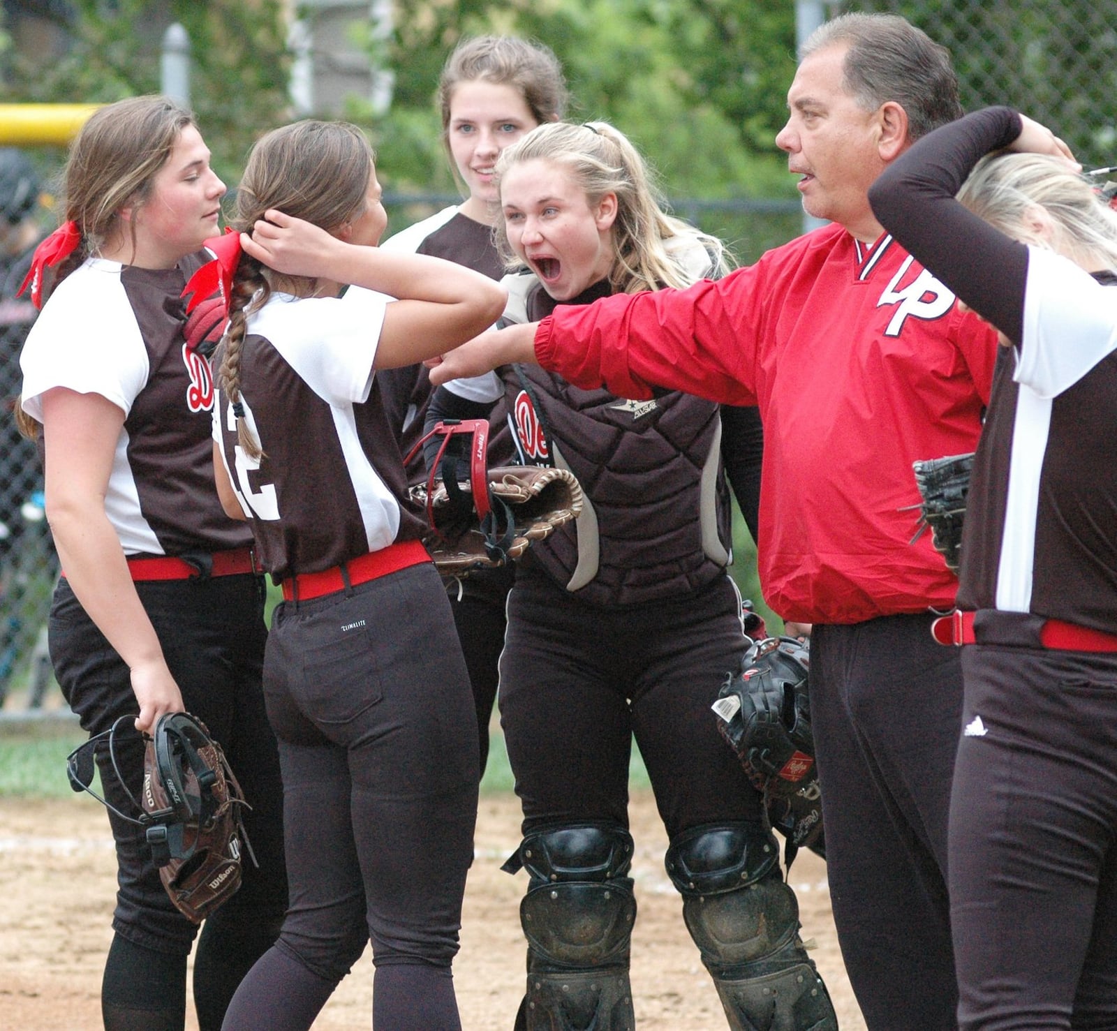 Deer Park catcher Torey Macke reacts in a huddle that includes coach John Schablein on Monday during a Division III district softball semifinal against Madison at Wyoming. Deer Park won 6-3. RICK CASSANO