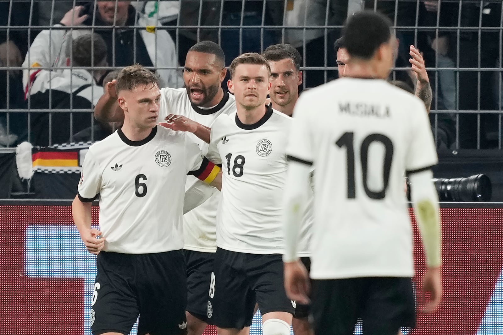 Germany's Joshua Kimmich, left, celebrates with teammates after scoring opening goal during the Nations League quarterfinal second leg soccer match between Germany and Italy at the Signal-Iduna Park in Dortmund, Germany, Sunday, March 23, 2025. (AP Photo/Martin Meissner)