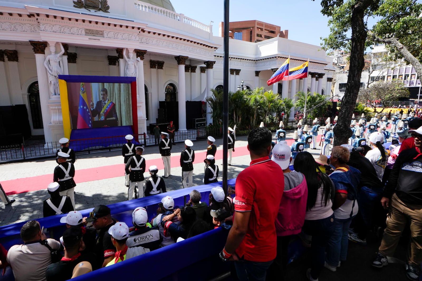 Government supporters and military guard listen to Venezuelan President Nicolas Maduro speak after his swearing-in ceremony for a third term as they watch a live video of him on a screen outside the National Assembly in Caracas, Venezuela, Friday, Jan. 10, 2025. (AP Photo/Matias Delacroix)