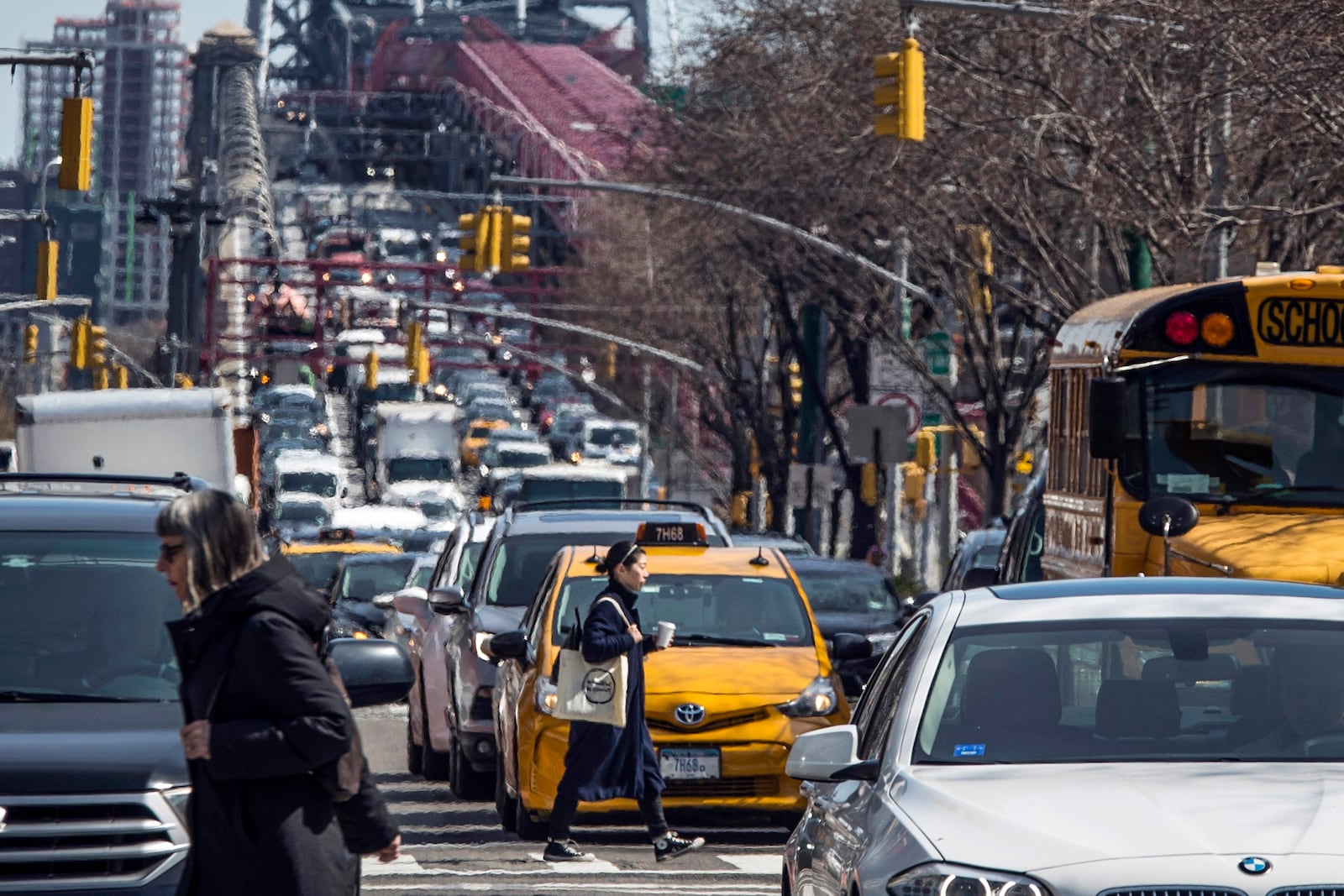 FILE - Pedestrians cross Delancey Street as congested traffic from Brooklyn enters Manhattan over the Williamsburg Bridge, March 28, 2019, in New York. (AP Photo/Mary Altaffer, File)