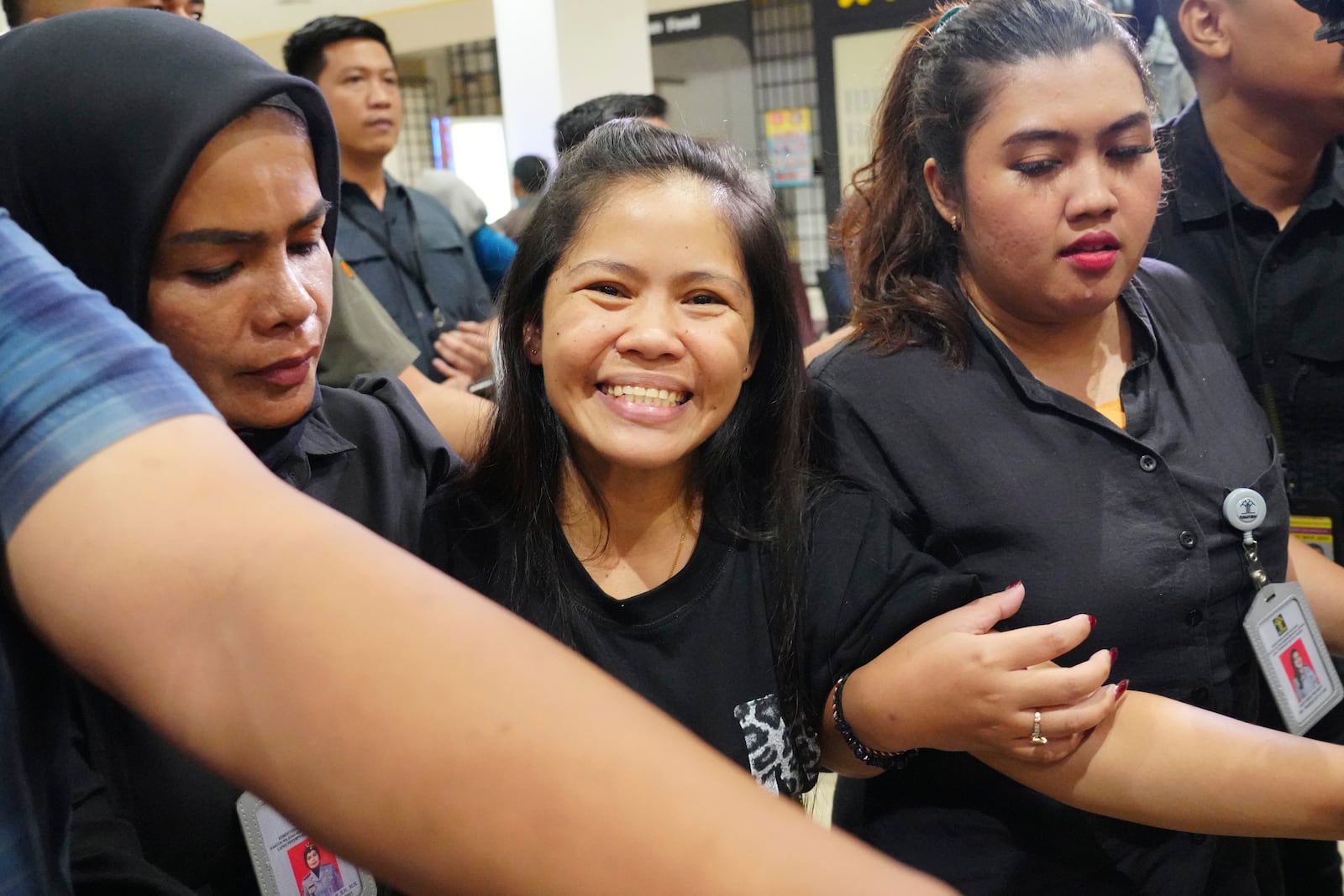 Mary Jane Veloso, center, a Filipina who was on death row in Indonesia and was nearly executed by firing squad in 2015, smiles as she arrives at Soekarno-Hatta International Airport for her repatriation to the Philippines, in Tangerang, Indonesia, Tuesday, Dec. 17, 2024. (AP Photo/Tatan Syuflana)