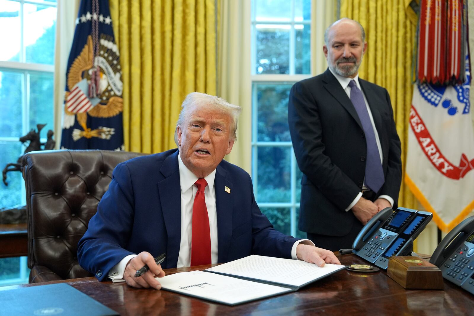 President Donald Trump speaks as Commerce Secretary Howard Lutnick listens in the Oval Office of the White House, Monday, Feb. 3, 2025, in Washington, as Trump prepares to sign an executive order. (AP Photo/Evan Vucci)