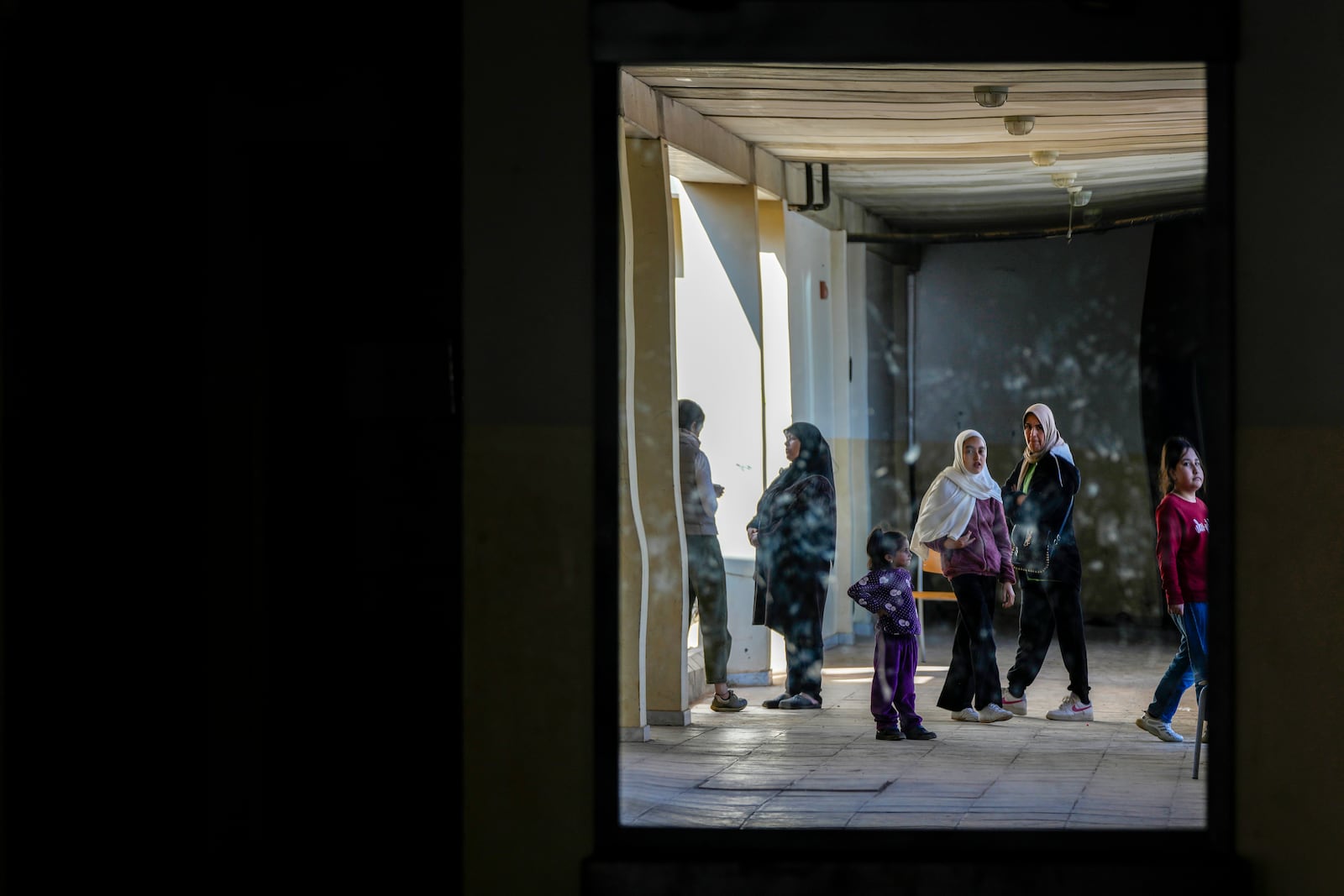 Displaced children, who fled Baalbek city and the nearby towns of Douris and Ain Bourday with their families amid the ongoing Hezbollah-Israel war, are reflected in a mirror inside a school being used as a shelter, in Deir Al-Ahmar, east Lebanon, Thursday, Oct. 31, 2024. (AP Photo/Hassan Ammar)