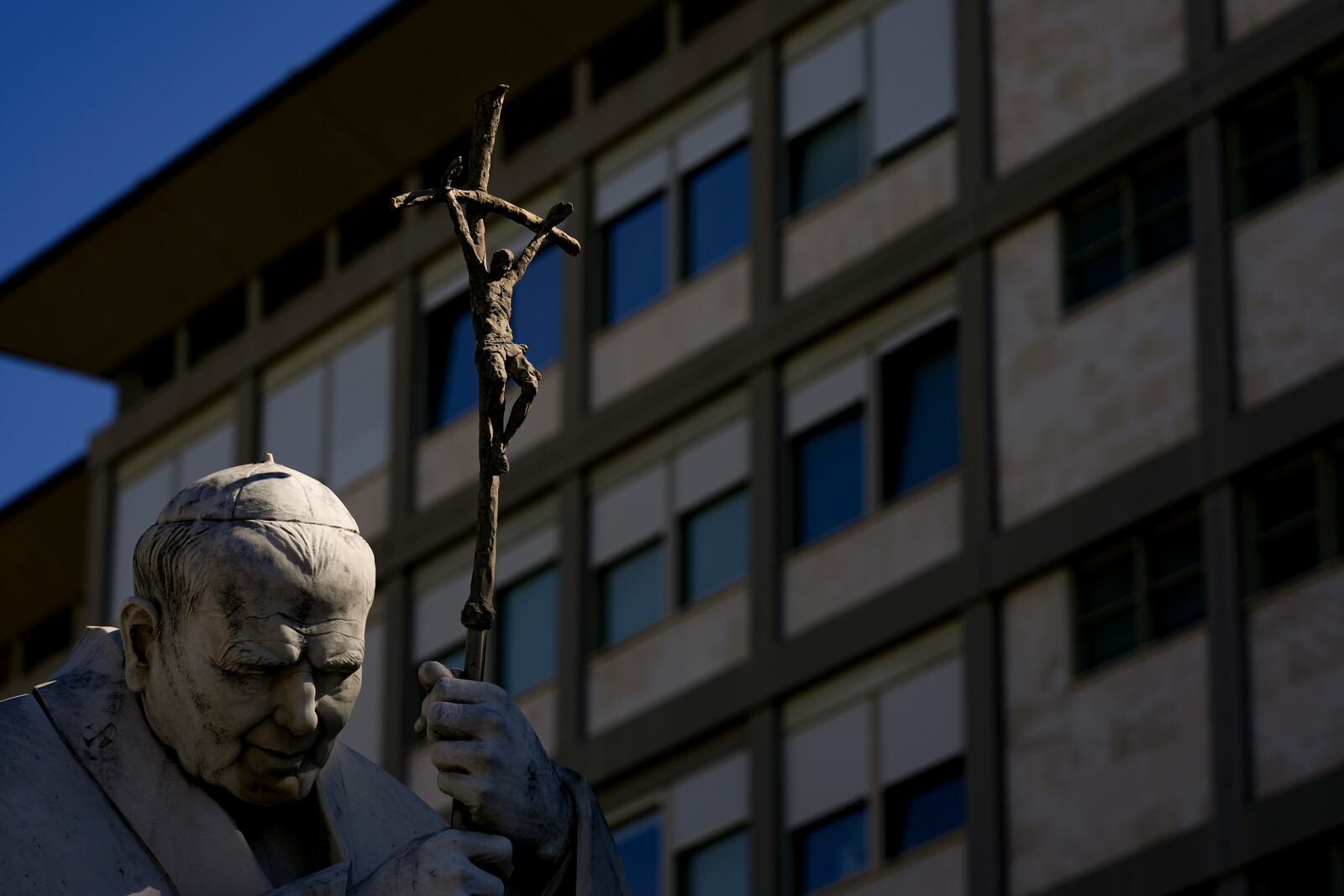 The sun shines over the statue of Pope John Paul II in front of the Agostino Gemelli Polyclinic, in Rome, Tuesday, March 18, 2025, where Pope Francis is hospitalized since Feb. 14. (AP Photo/Andrew Medichini)