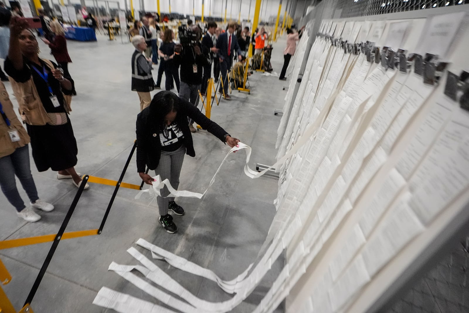 An elections staffer hangs scanner tapes used in early voting at the Fulton County Election Hub and Operation Center, Tuesday, Nov. 5, 2024, in Atlanta. (AP Photo/John Bazemore)