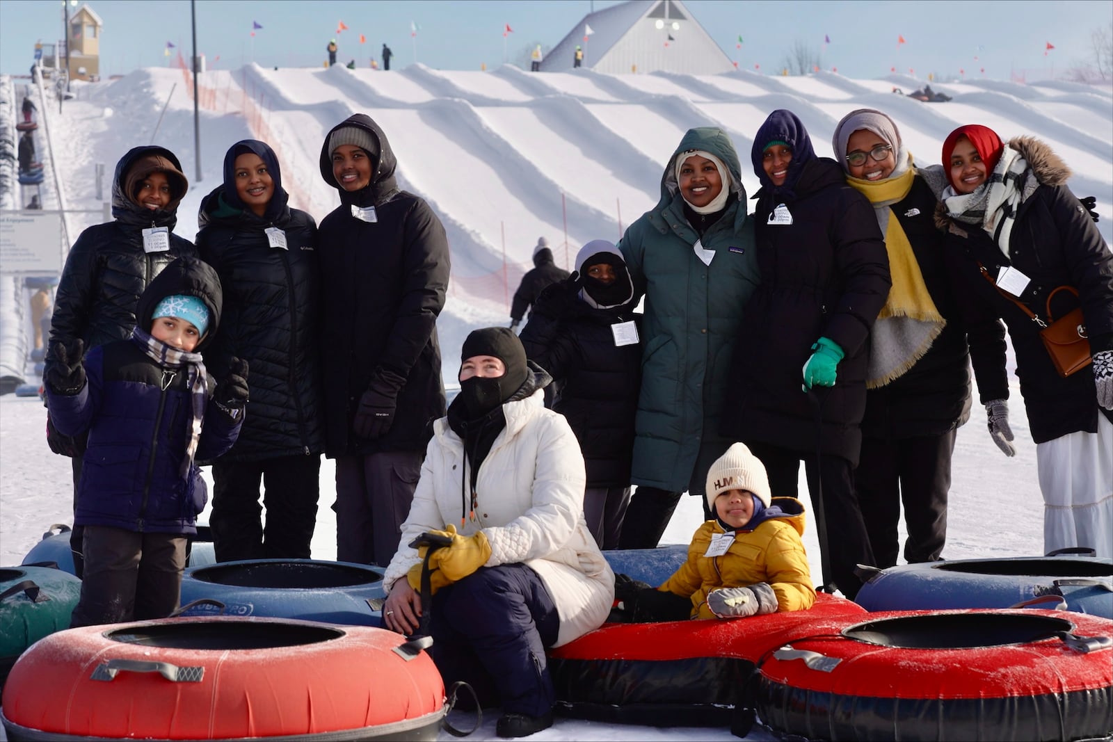 Nasrieen Habib, center right with green coat, and some of the members of the outdoors group she founded for Muslim women pose for a photo at the bottom of a snow tubing hill at Elm Creek Park Reserve in Maple Grove, Minn., on Jan. 4, 2025. (AP Photo/Mark Vancleave)