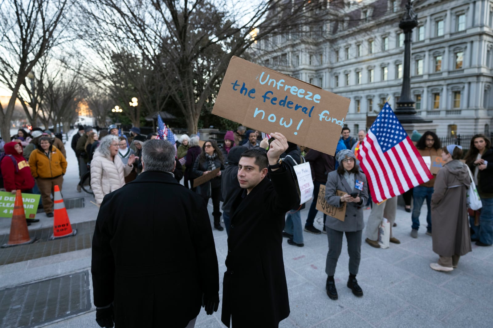 People protest against a funding freeze of federal grants and loans following a push from President Donald Trump to pause federal funding near to the White House in Washington, Tuesday, Jan. 28, 2025. (AP Photo/Ben Curtis)