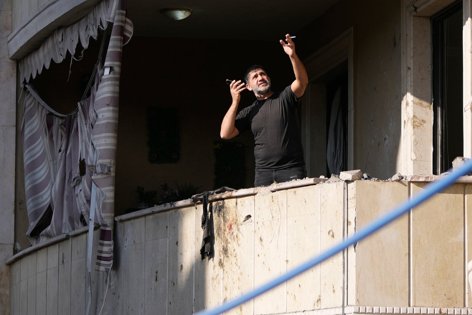 A resident gestures as he speaks on his mobile phone while checking his apartment at the site of an Israeli airstrike in Aramoun village, southeast of Beirut, Lebanon, Wednesday, Nov. 13, 2024. (AP Photo/Hassan Ammar)