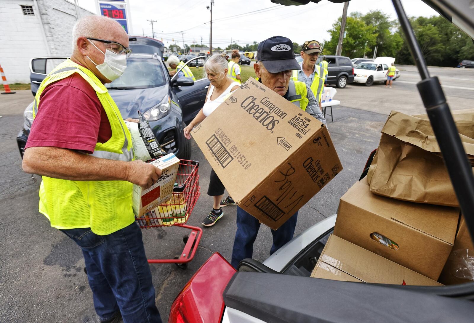 Frank Suttmiller, left, and Charlie Withrow load a car during a food distribution Wednesday, Aug. 3, 2021, at Village Food Pantry in New Miami. The pantry provides food for nearly 200 families a week. NICK GRAHAM/STAFF