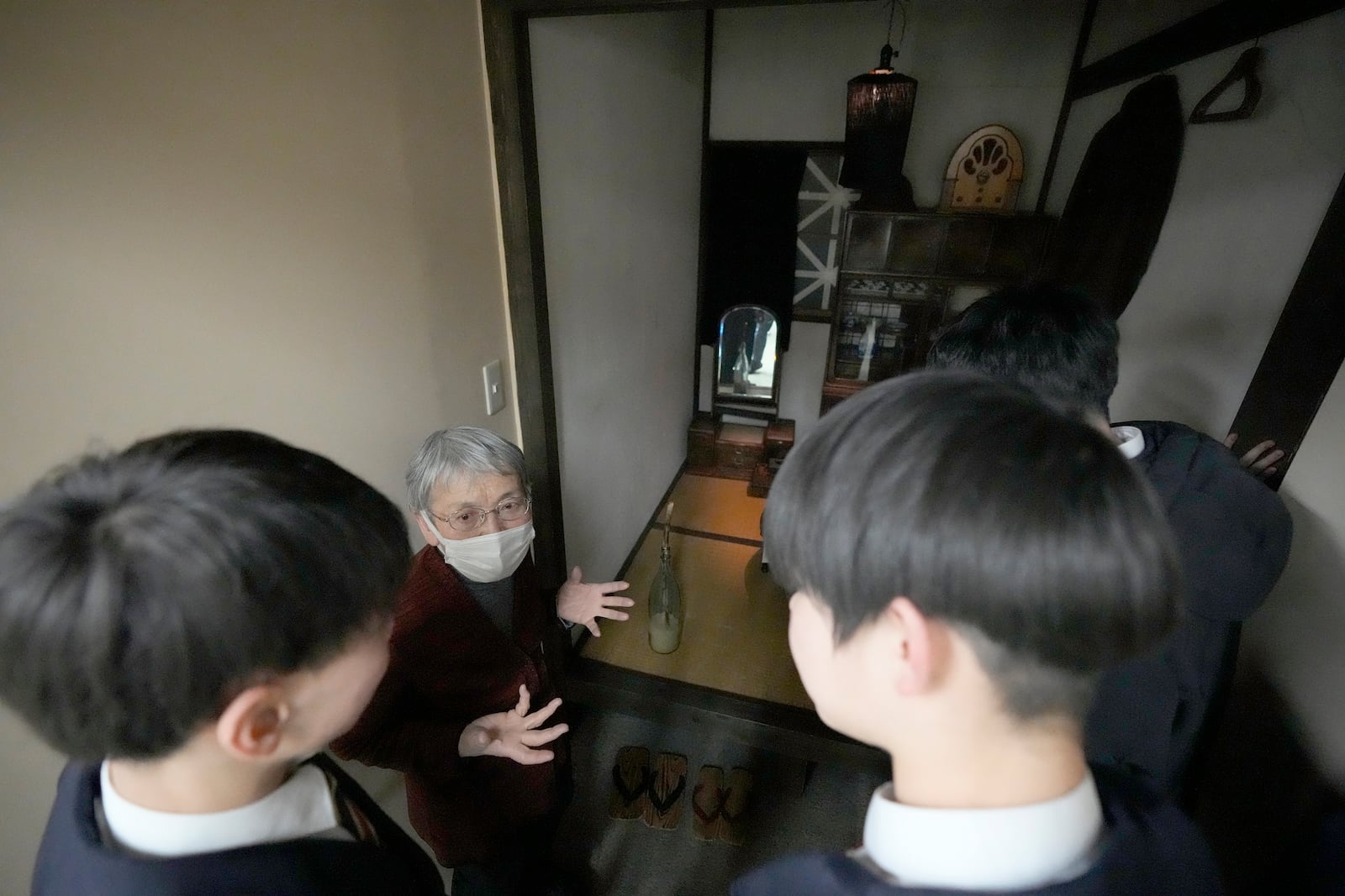 A staff member explains to middle school students from Niigata on a school trip as they look at an unit representing a room from a home during the Tokyo Air Raids at the Center of the Tokyo Raids and War Damage on Feb. 24, 2025, in Tokyo. (AP Photo/Eugene Hoshiko)