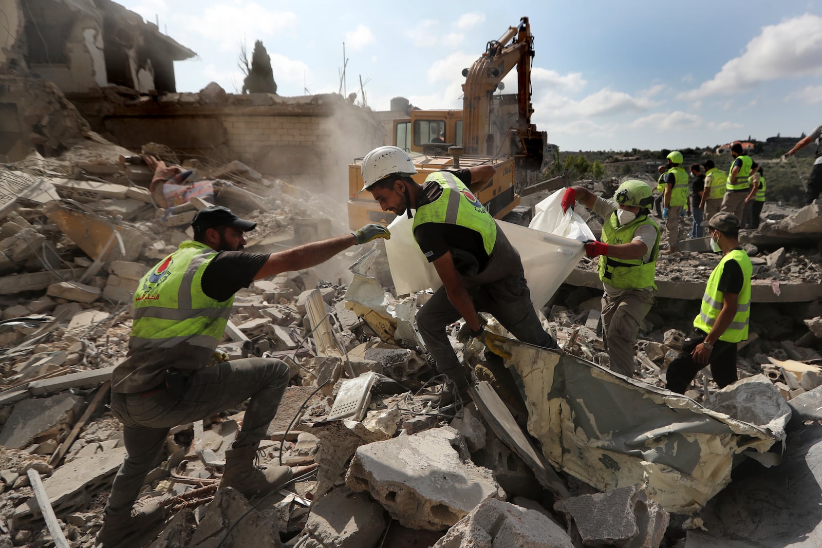 Rescue workers carry remains of dead people at the site that was hit by Israeli airstrikes in Qana village, south Lebanon, Wednesday, Oct. 16, 2024. (AP Photo/Mohammed Zaatari)