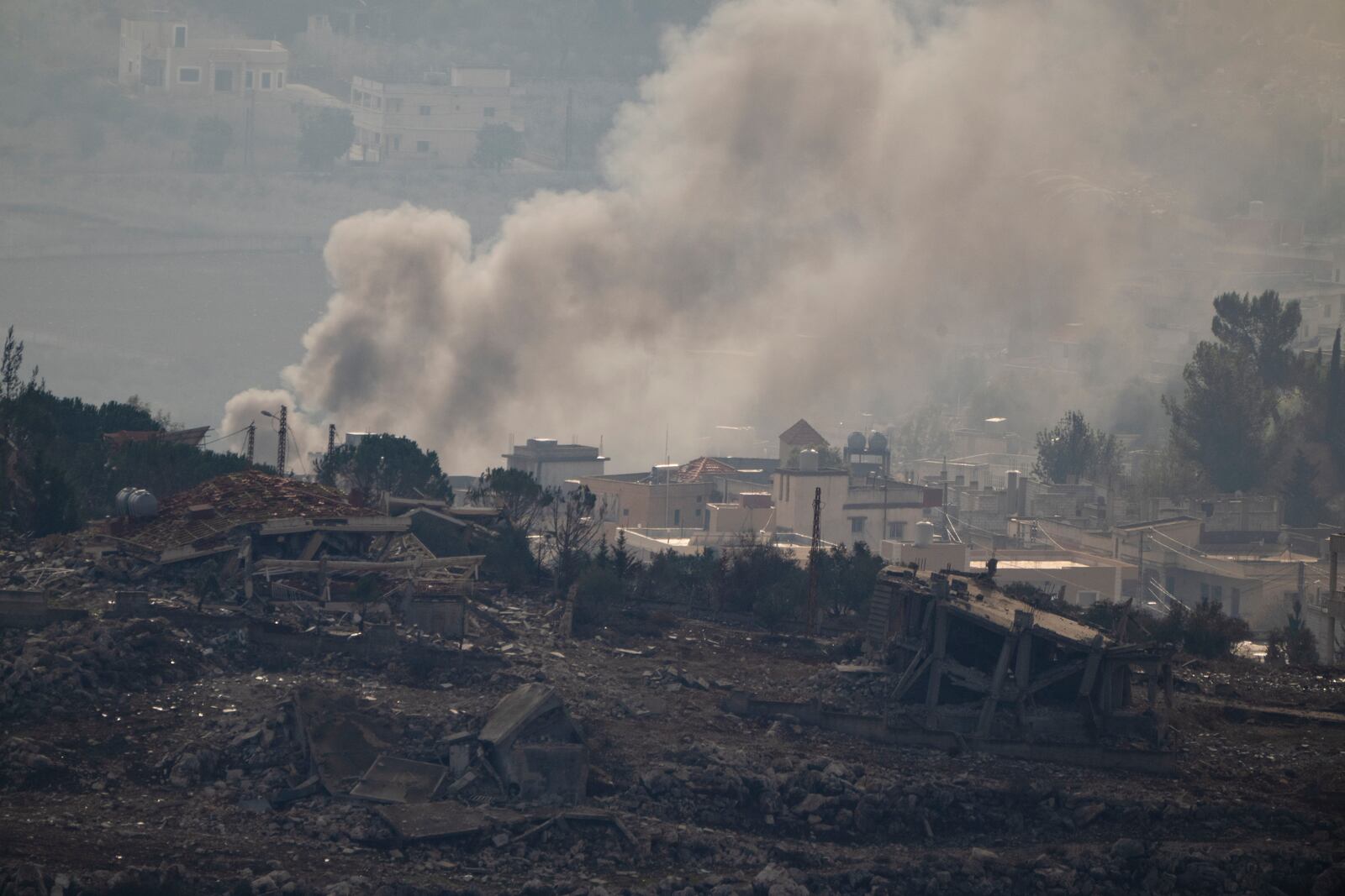 Smoke rise next to damaged buildings on an area of a village in southern Lebanon, as seen from the Kibbutz Manara, northern Israel, Thursday, Nov. 28, 2024. (AP Photo/Leo Correa)