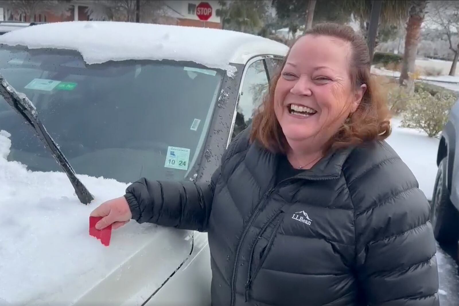 In this image taken from video, Terry Fraser of Cape Cod, Mass., uses a discount card to scrape snow and ice off her rental SUV on Sept. 22, 2025 in Brunswick, Ga., where nobody owns ice scrapers. (AP Photo/Russ Bynum)