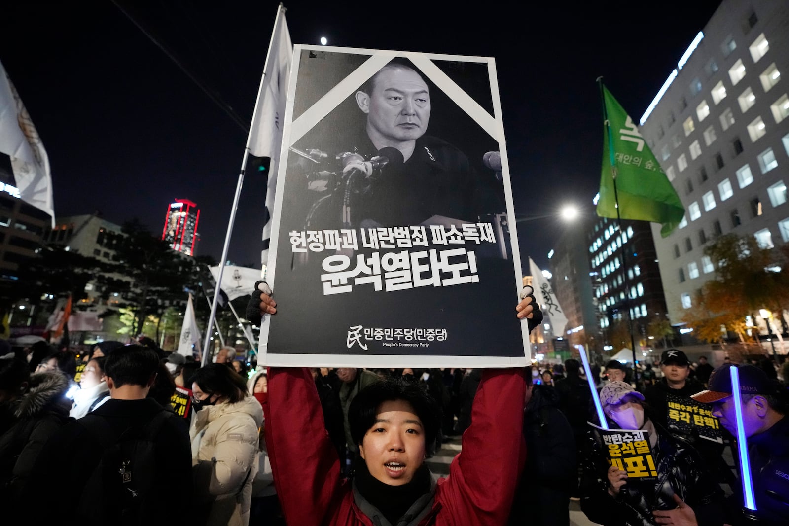 A participant holds up a banner with writing reading "Overthrow the rebellion criminal Yoon Suk Yeol", during a rally to demand South Korean President Yoon Suk Yeol's impeachment, outside the National Assembly in Seoul, South Korea, Wednesday, Dec. 11, 2024. (AP Photo/Ahn Young-joon)